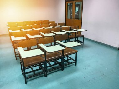 Sınıfın arka planında tahta sandalyeler var.