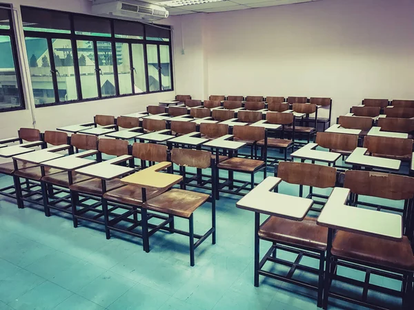 Sınıfın arka planında tahta sandalyeler var.