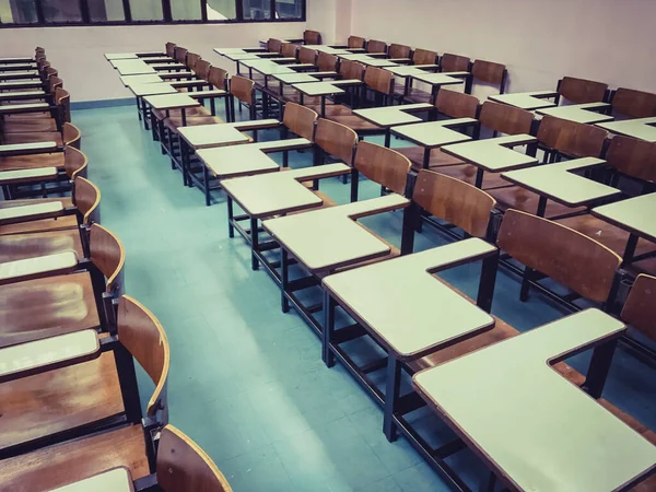 Sınıfın arka planında tahta sandalyeler var.