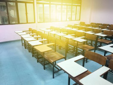 Sınıfın arka planında tahta sandalyeler var.
