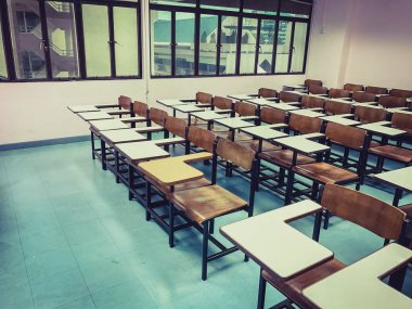 Sınıfın arka planında tahta sandalyeler var.