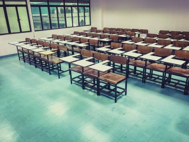 Sınıfın arka planında tahta sandalyeler var.