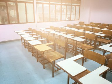 Sınıfın arka planında tahta sandalyeler var.
