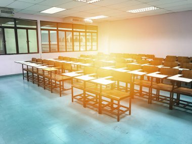 Sınıfın arka planında tahta sandalyeler var.