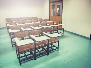 Sınıfın arka planında tahta sandalyeler var.