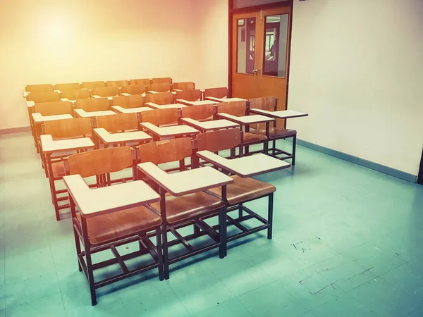 Sınıfın arka planında tahta sandalyeler var.