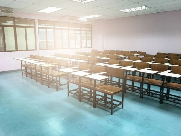 Sınıfın arka planında tahta sandalyeler var.