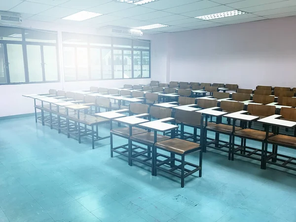 Sınıfın arka planında tahta sandalyeler var.