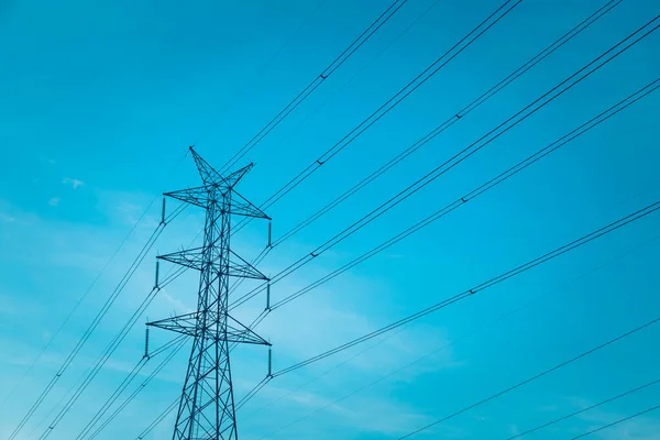 Gün batımından önce mavi gökyüzü olan yüksek voltajlı posta kulesi.