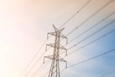 Gün batımından önce mavi gökyüzü olan yüksek voltajlı posta kulesi.