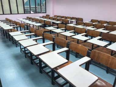 Sınıfın arka planında tahta sandalyeler var.