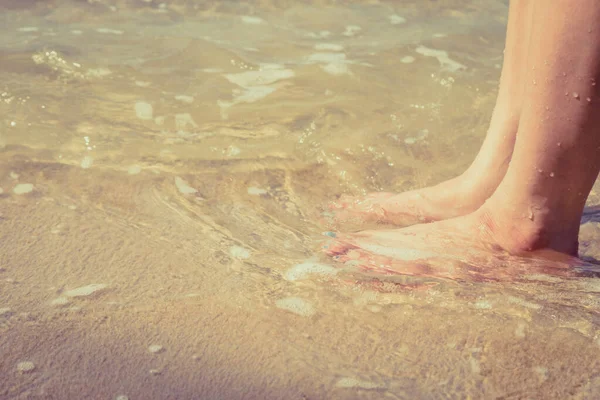 Deniz suyu geçmişi olan kumsala ayak basan kadın.