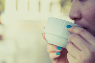 Arka planda bulanık kahve içen kadın.