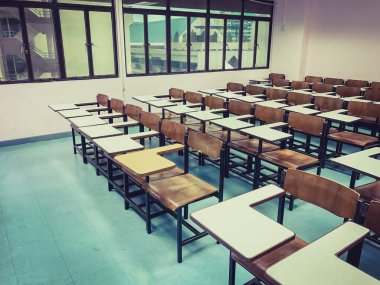 Sınıfın arka planında tahta sandalyeler var.