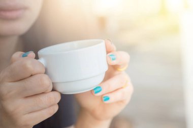 Arka planda bulanık kahve içen kadın.