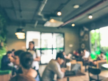 Kafede arka planda bir sürü müşterinin bulanık görüntüsü.