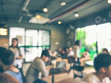 Kafede arka planda bir sürü müşterinin bulanık görüntüsü.