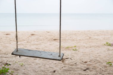 Sahilde ahşap salıncak ve kum arka planı