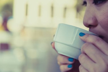 Arka planda bulanık kahve içen kadın.