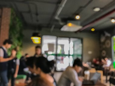 Kafede arka planda bir sürü müşterinin bulanık görüntüsü.