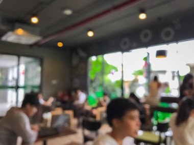 Kafede arka planda bir sürü müşterinin bulanık görüntüsü.