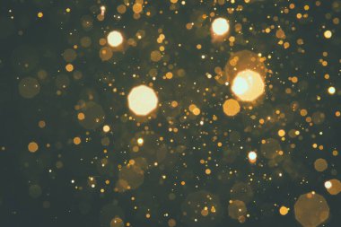 Soyut bulanık altın sarısı, siyah arkaplanlı parıltı bokeh