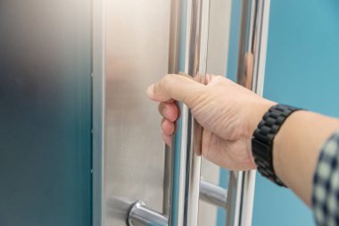 Elle açılan metal, modern ofis kapısı.