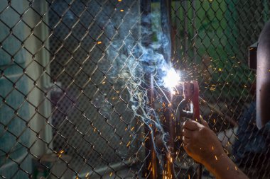 Kaynakçılar karanlık arka plandaki mülkü korumak için kapıları kaynaklıyorlar.