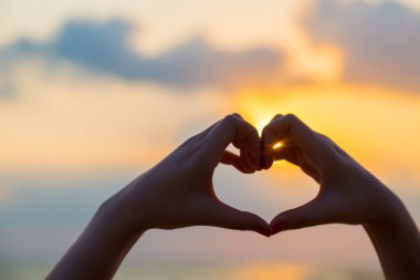 Eller kalp şeklinde aşk yapar. Gün batımında siluetle.