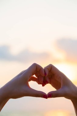 Eller kalp şeklinde aşk yapar. Gün batımında siluetle.