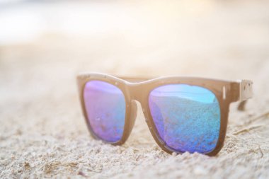 Beyaz kum zemininde mavi güneş gözlüğü