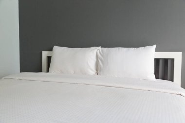 Yatak odasında iki beyaz yastık ve battaniye.