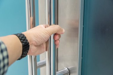 Elle açılan metal, modern ofis kapısı.