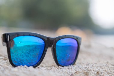 Beyaz kum zemininde mavi güneş gözlüğü