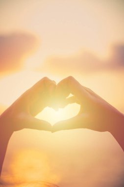 Eller kalp şeklinde aşk yapar. Gün batımında siluetle.