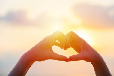 Eller kalp şeklinde aşk yapar. Gün batımında siluetle.