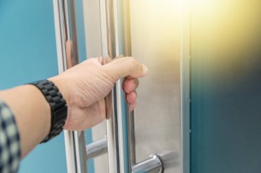 Elle açılan metal, modern ofis kapısı.