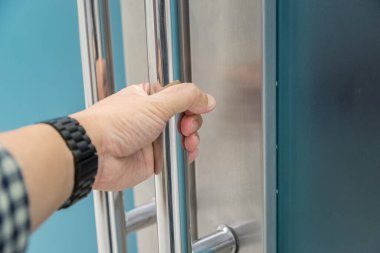 Elle açılan metal, modern ofis kapısı.