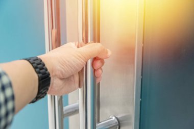 Elle açılan metal, modern ofis kapısı.