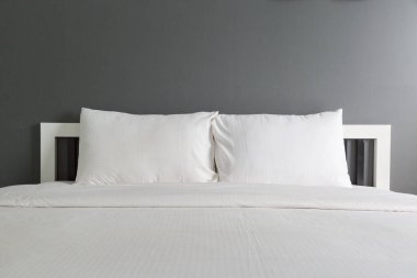 Yatak odasında iki beyaz yastık ve battaniye.