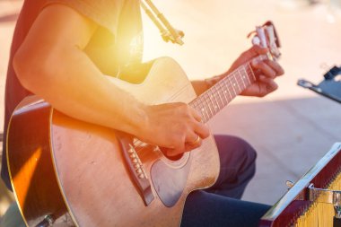 Hipster, arka planı bulanık bir şekilde eski bir tahta gitarı mutlu bir anda çalıyor.