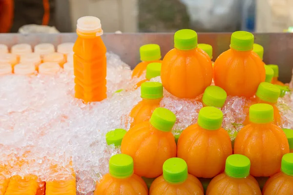 冷たいオレンジジュースは 氷の背景とさわやかなために飲む準備ができてボトルに — ストック写真