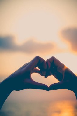Eller kalp şeklinde aşk yapar. Gün batımında siluetle.