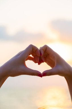 Eller kalp şeklinde aşk yapar. Gün batımında siluetle.