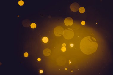 Siyah arkaplanda koyu soyut altın bokeh parıltısı