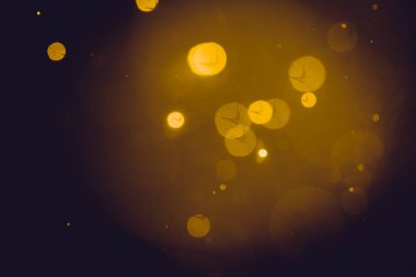 Siyah arkaplanda koyu soyut altın bokeh parıltısı