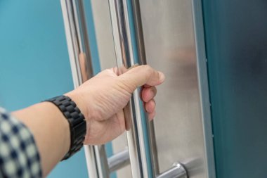 Elle açılan metal, modern ofis kapısı.