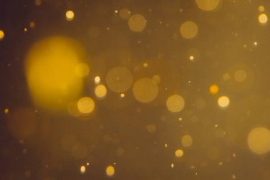 Siyah arkaplanda koyu soyut altın bokeh parıltısı