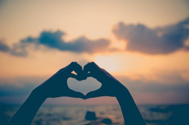 Eller kalp şeklinde aşk yapar. Gün batımında siluetle.