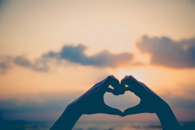 Eller kalp şeklinde aşk yapar. Gün batımında siluetle.